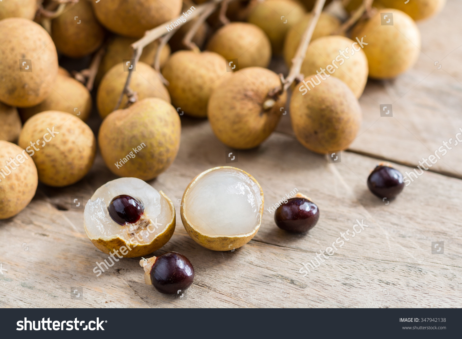 Longan Fresh (Dimocarpus longan.)A bunch of Longan and Peel show the white meat with black seed was placed on a wooden background.