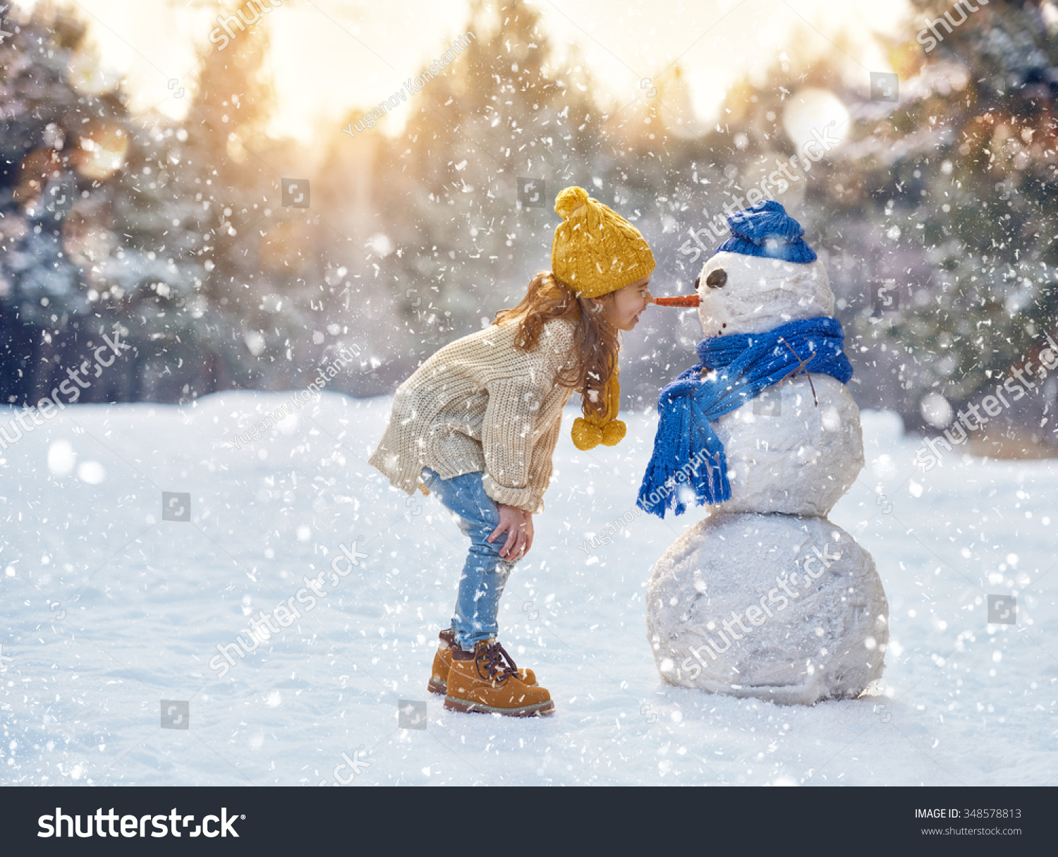 happy child girl plaing with a snowman on a snowy winter walk