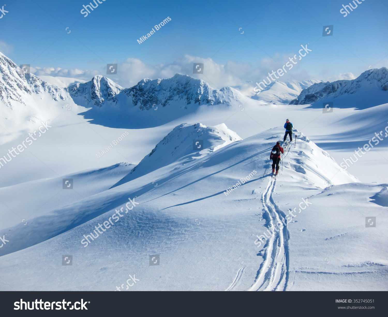 High altitude view of two skiers walking on a mountain ridge in the Lyngen Alps  Norway
