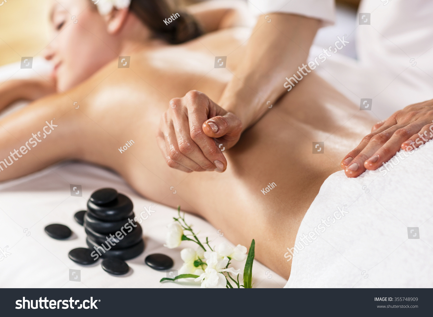 Young beautiful woman enjoying massage on the table at spa center