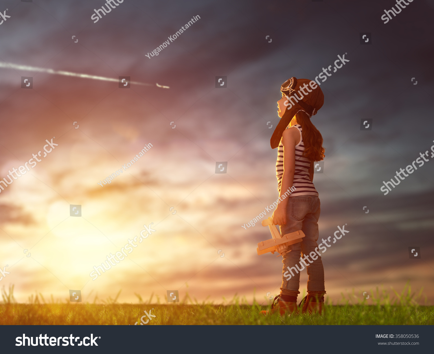 dreams of flight! child playing with toy airplane against the sky at sunset