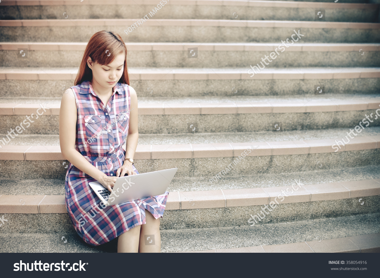 female university student using mobile on stairs