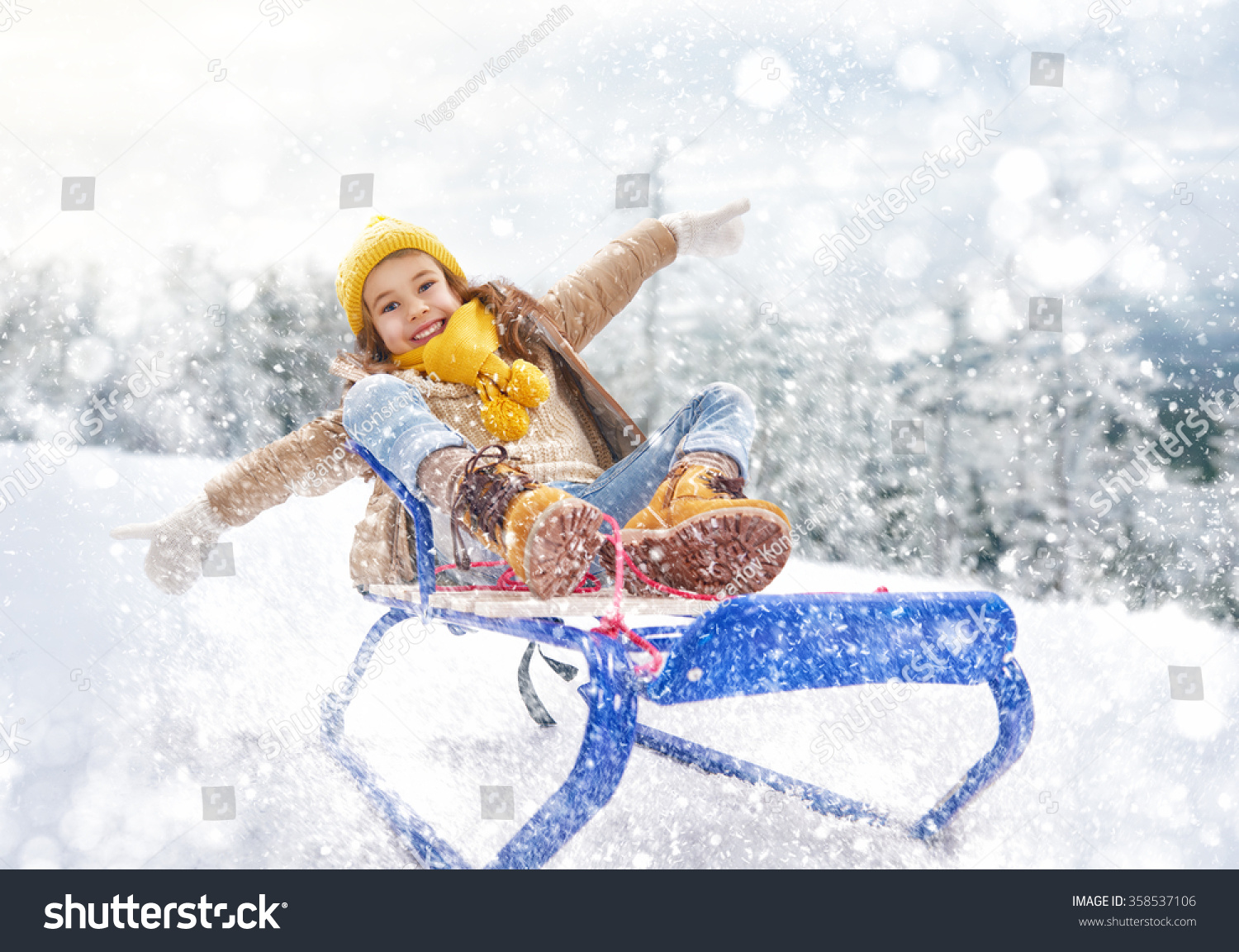 Child sledding. Little girl enjoying a sleigh ride. Child girl riding a sledge. Child plays outdoors in snow. Outdoor fun for family winter vacation.