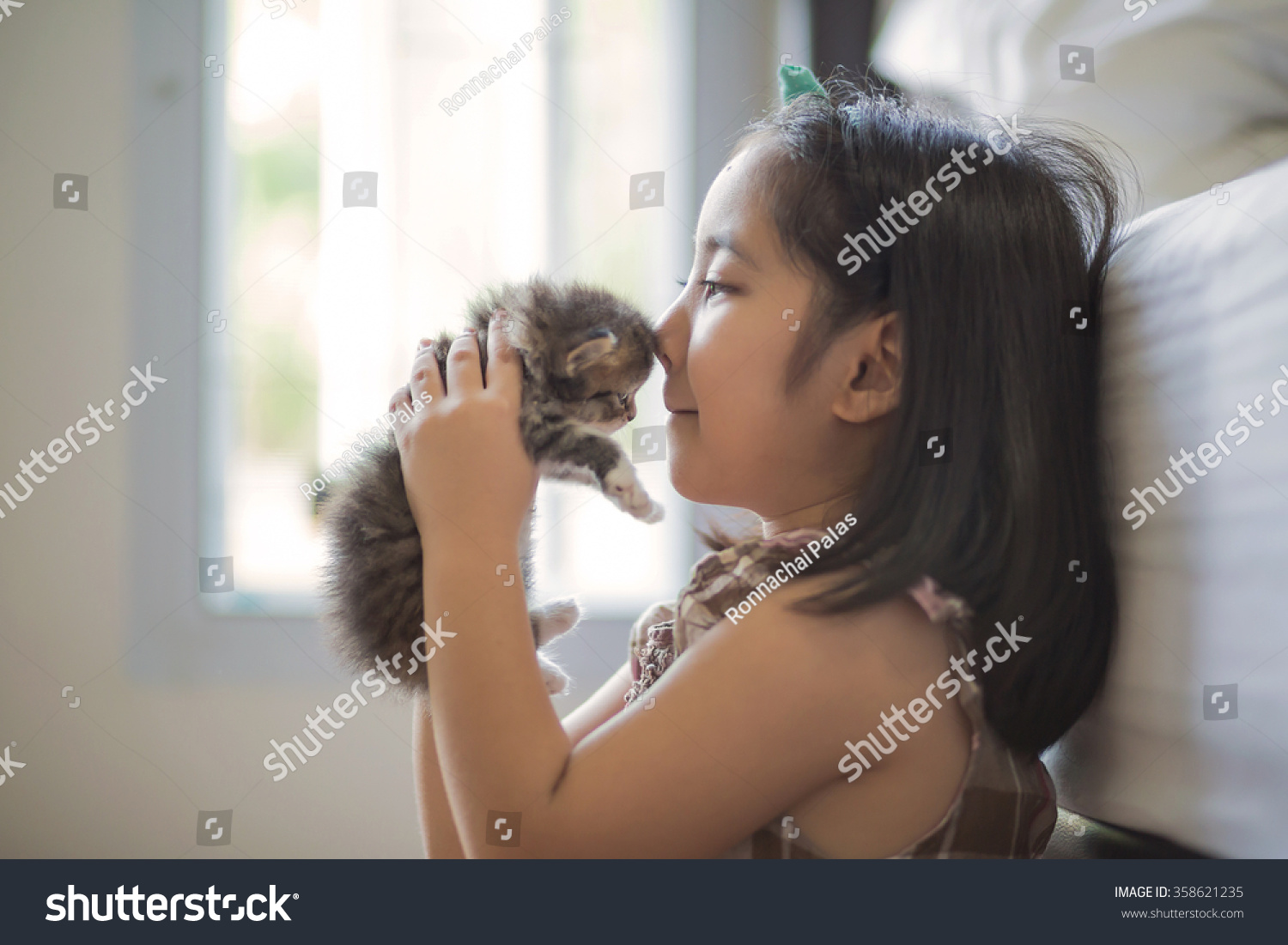 Adorable little asian girl kissing her kitten