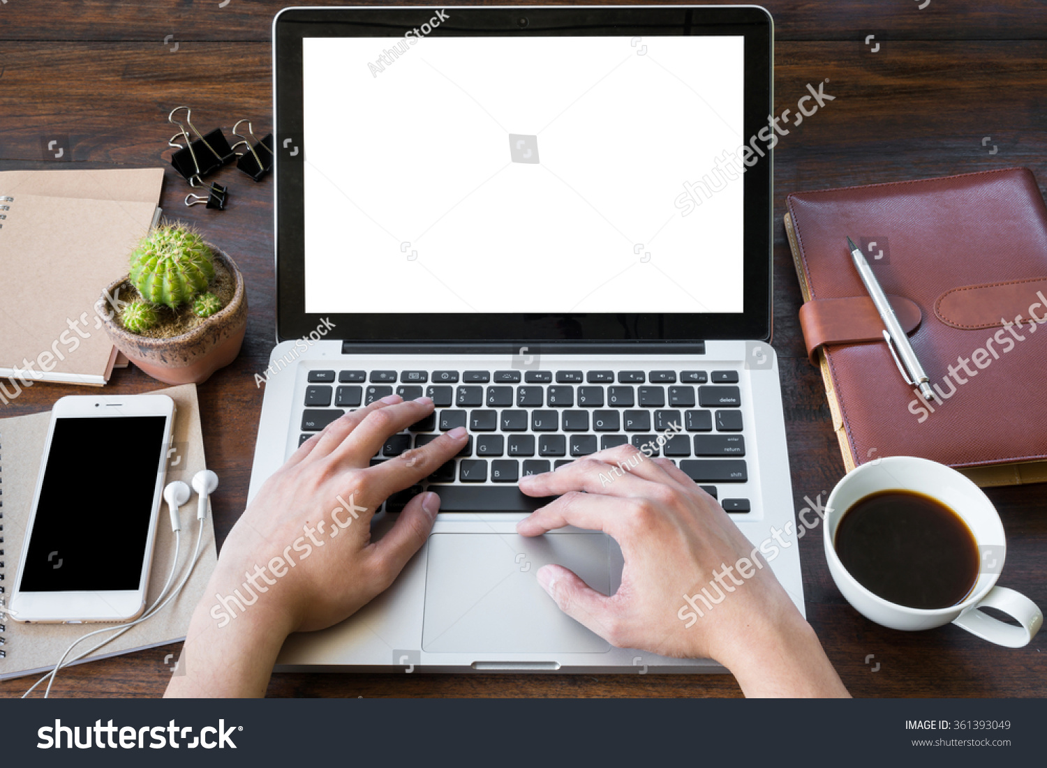 A man is working by using a laptop computer on vintage wooden table. Hand typing on a keyboard. Front view.