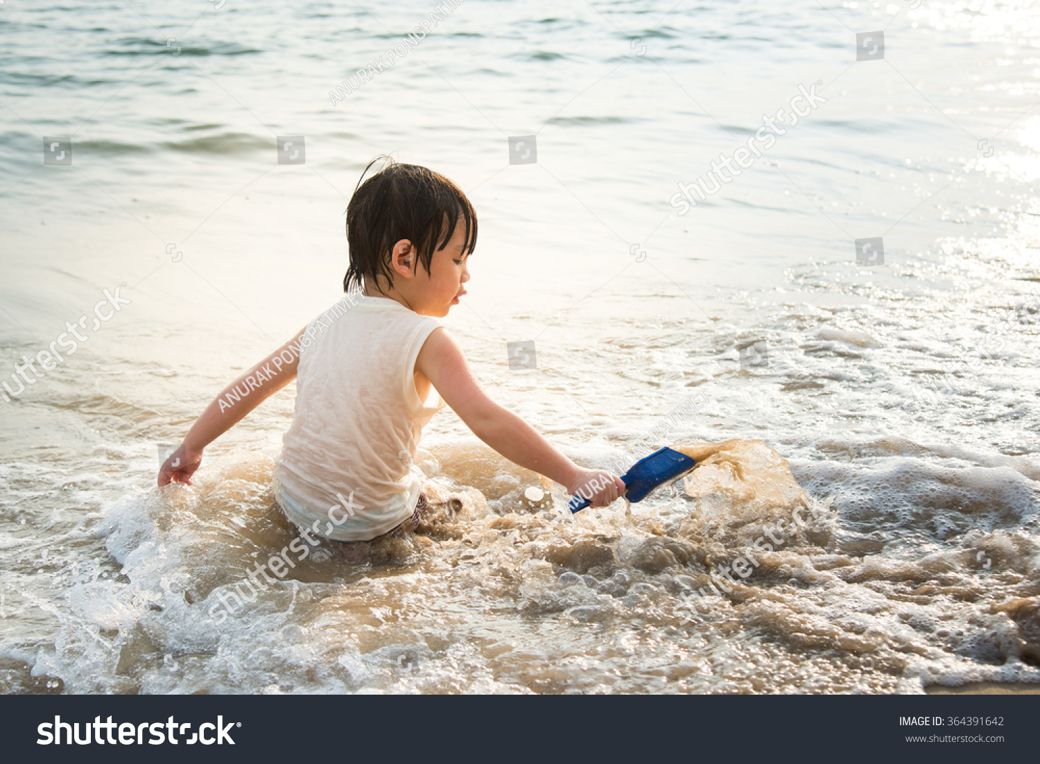 Cute asian boy playing on the beach  at the sunset time