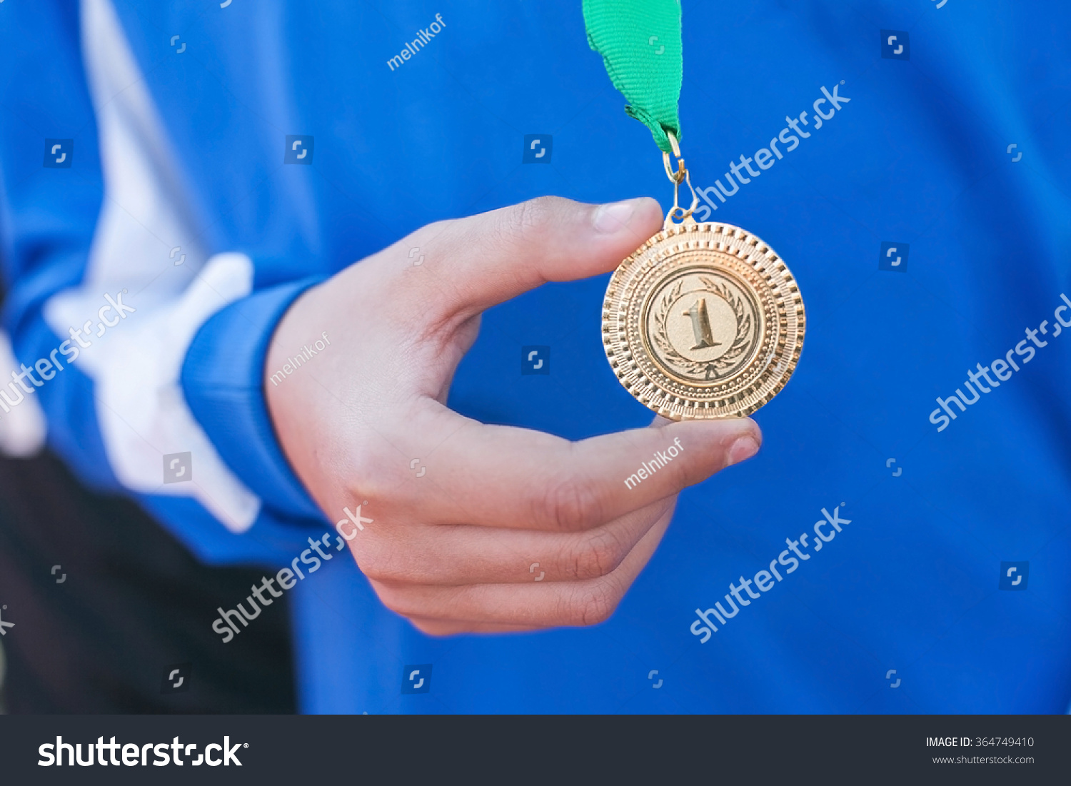 Hand of the man and medal close up. The winner holds a medal. Victory in competitions. First place. The hand holding a gold medal. Soccer winner.