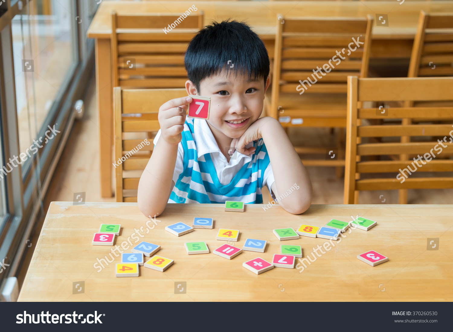Asian Boy With Wooden Toy Plate Numbers On Wood Table  He Show  plate Numbers In His Hand