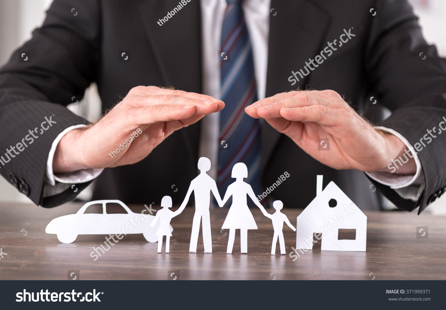 Concept of insurance with hands over a house  a car and a family