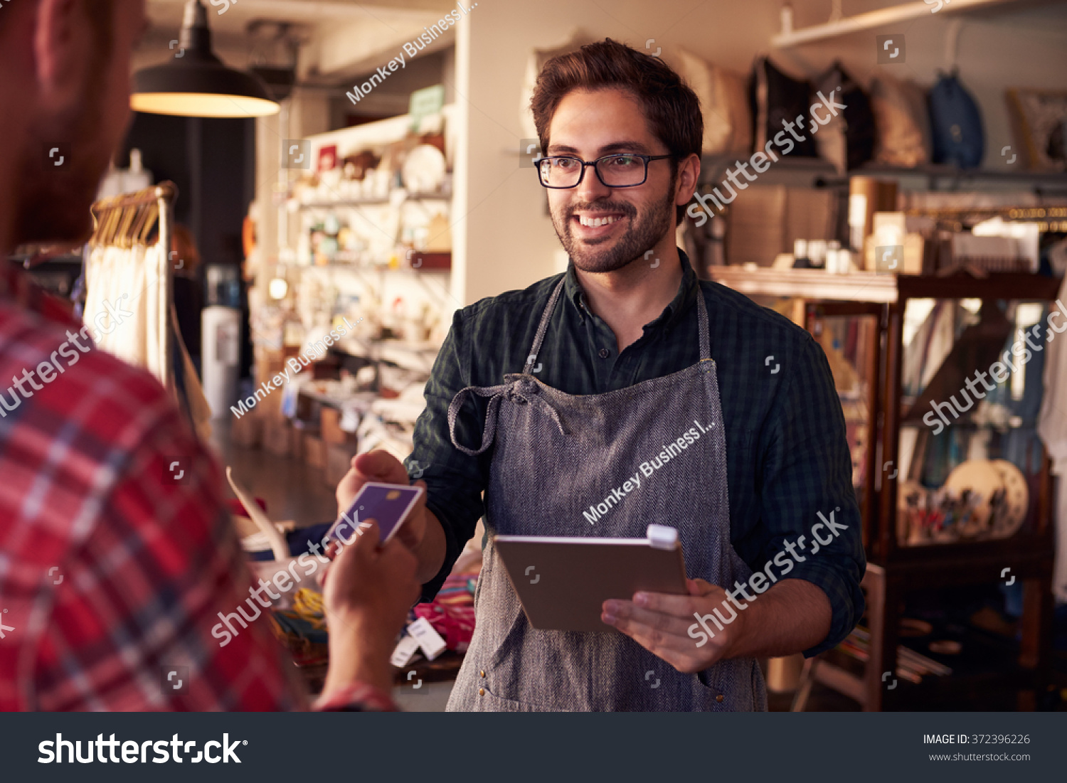 Sales Assistant With Credit Card Reader On Digital Tablet