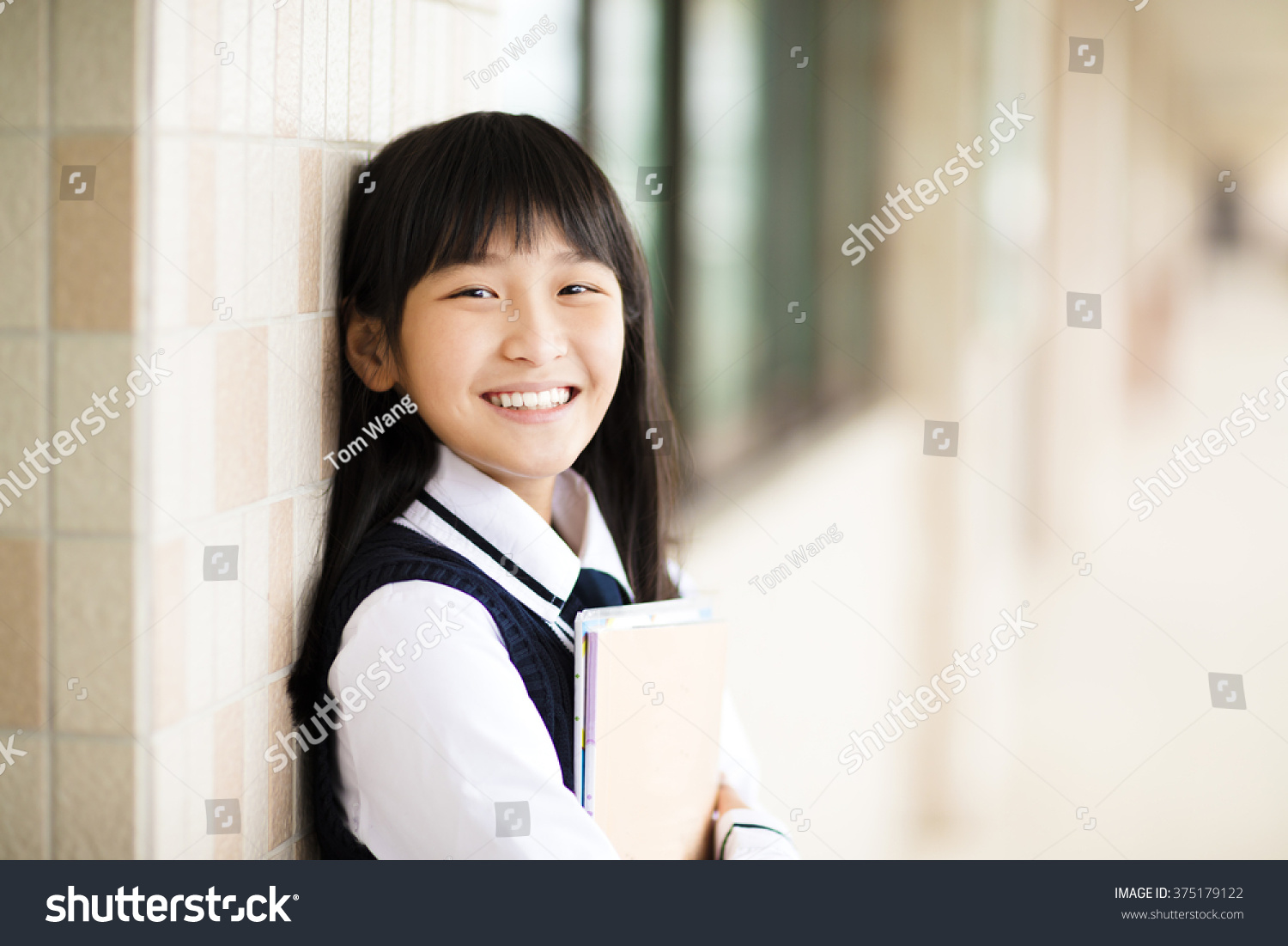 pretty  student girl holding books in front of  classroom