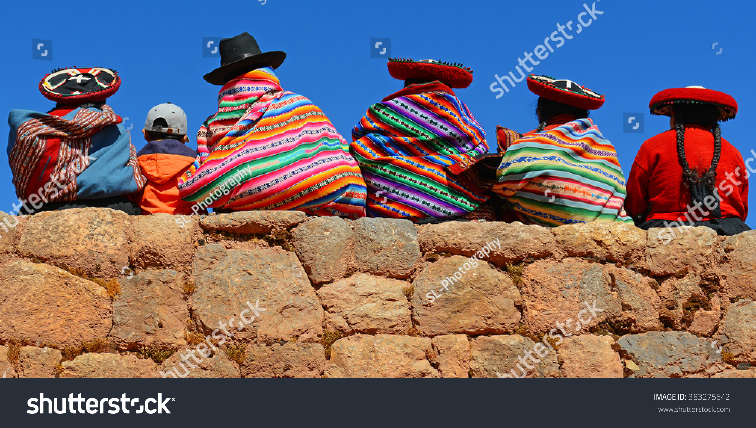 Quechua ladies and a young boy chatting on an ancient Inca wall.