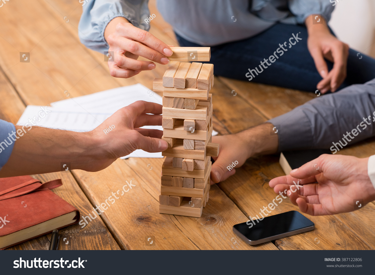 Close up of hands helping build a building of wooden pieces. Businesspeople planning a new business strategy. Business team trying to generate new ideas with wooden bricks. Business risk concept.
