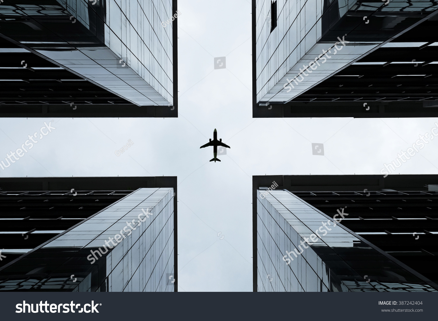 Silhouette of an airplane flying into the crosshair of a symmetrical highrise building.
