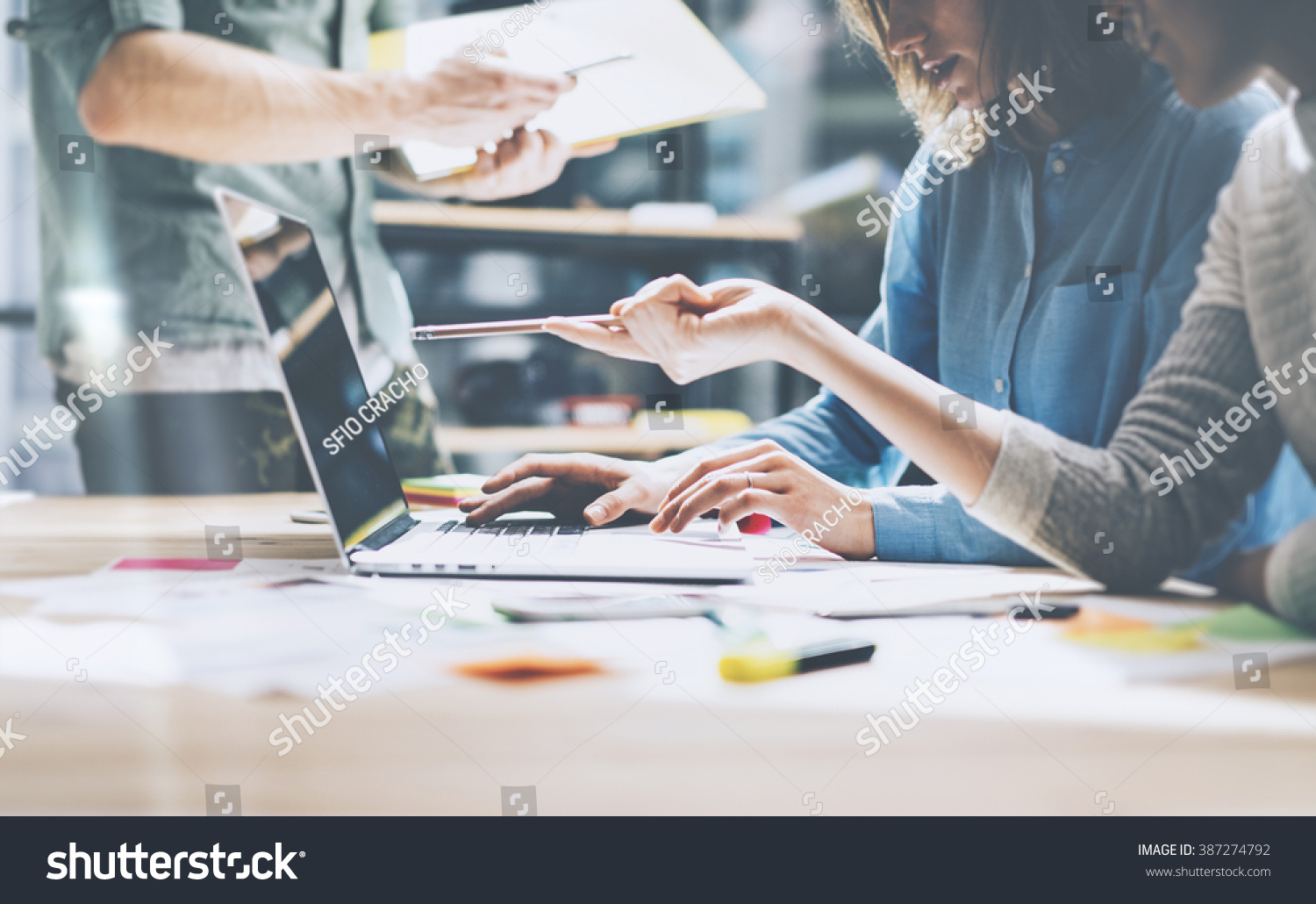 Team job. Photo young businessmans crew working with new startup project in modern loft. Generic design notebook on wood table. Horizontal film effect
