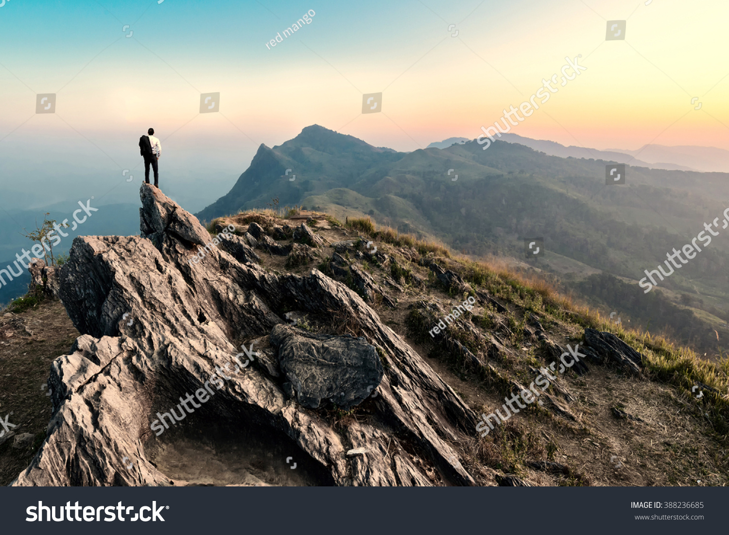 businessman hike on the peak of rocks mountain at sunset  success winner  leader concept