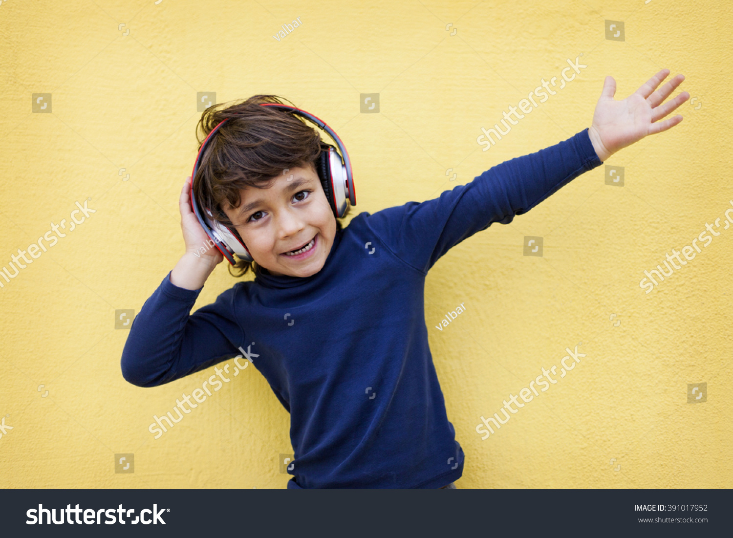 kid using headphones on yellow wall