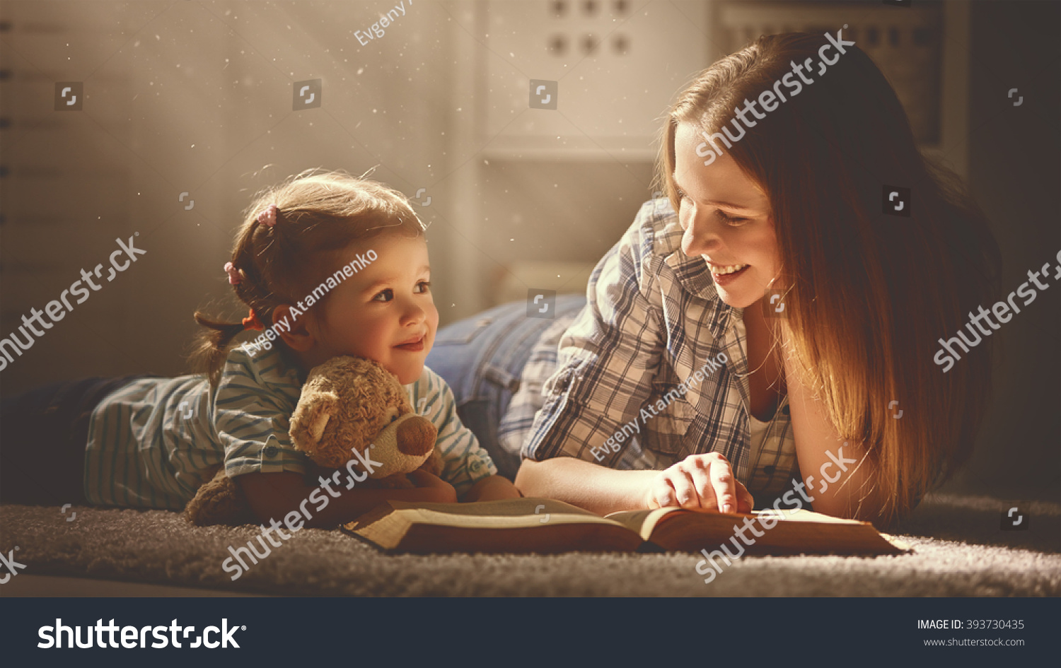 happy family mother and daughter read a book in the evening at home