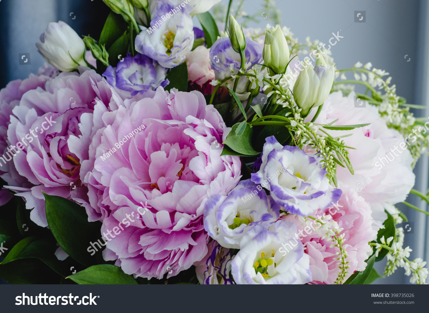 Rich bunch of pink peonies and lilac eustoma roses flowers green leaf in glass vase. Fresh spring bouquet. Summer Background