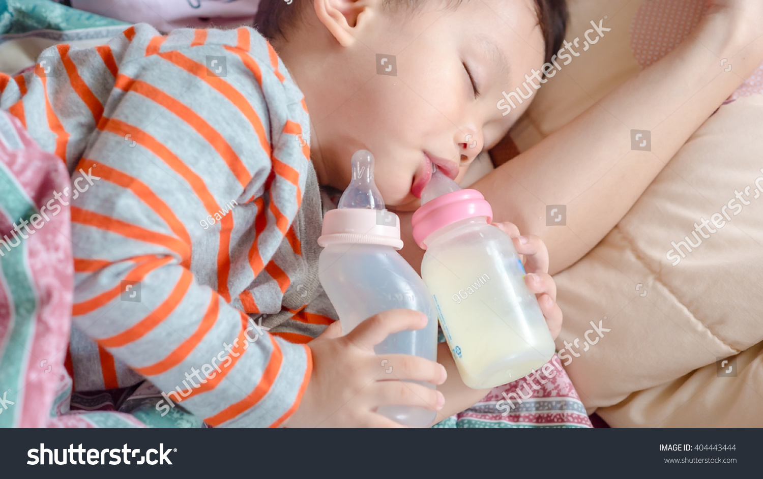   milk bottle and water bottle holding by asian  boy.The kids sleeping in mother arm 