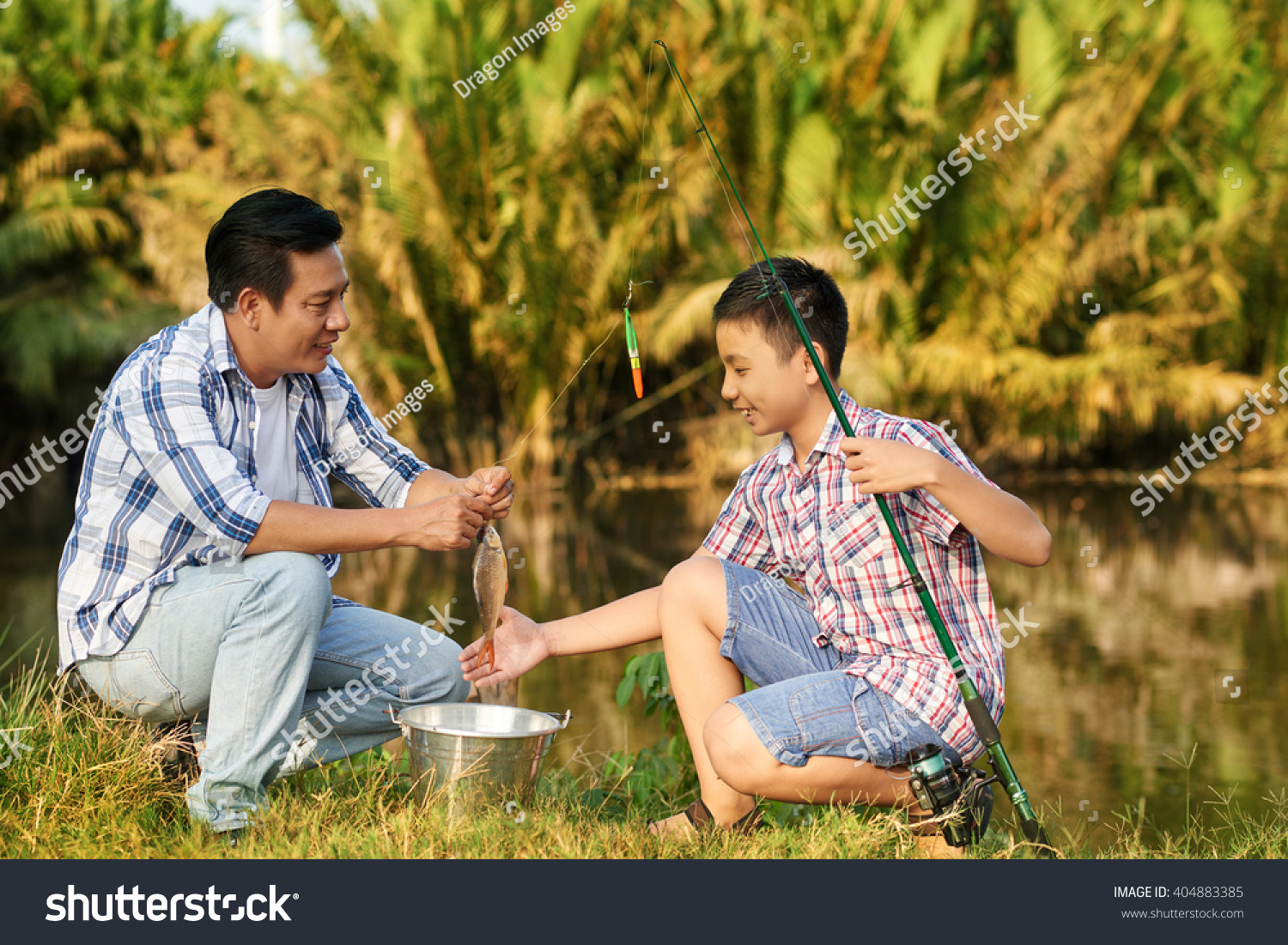 Asian man and teenage boy excited with catch