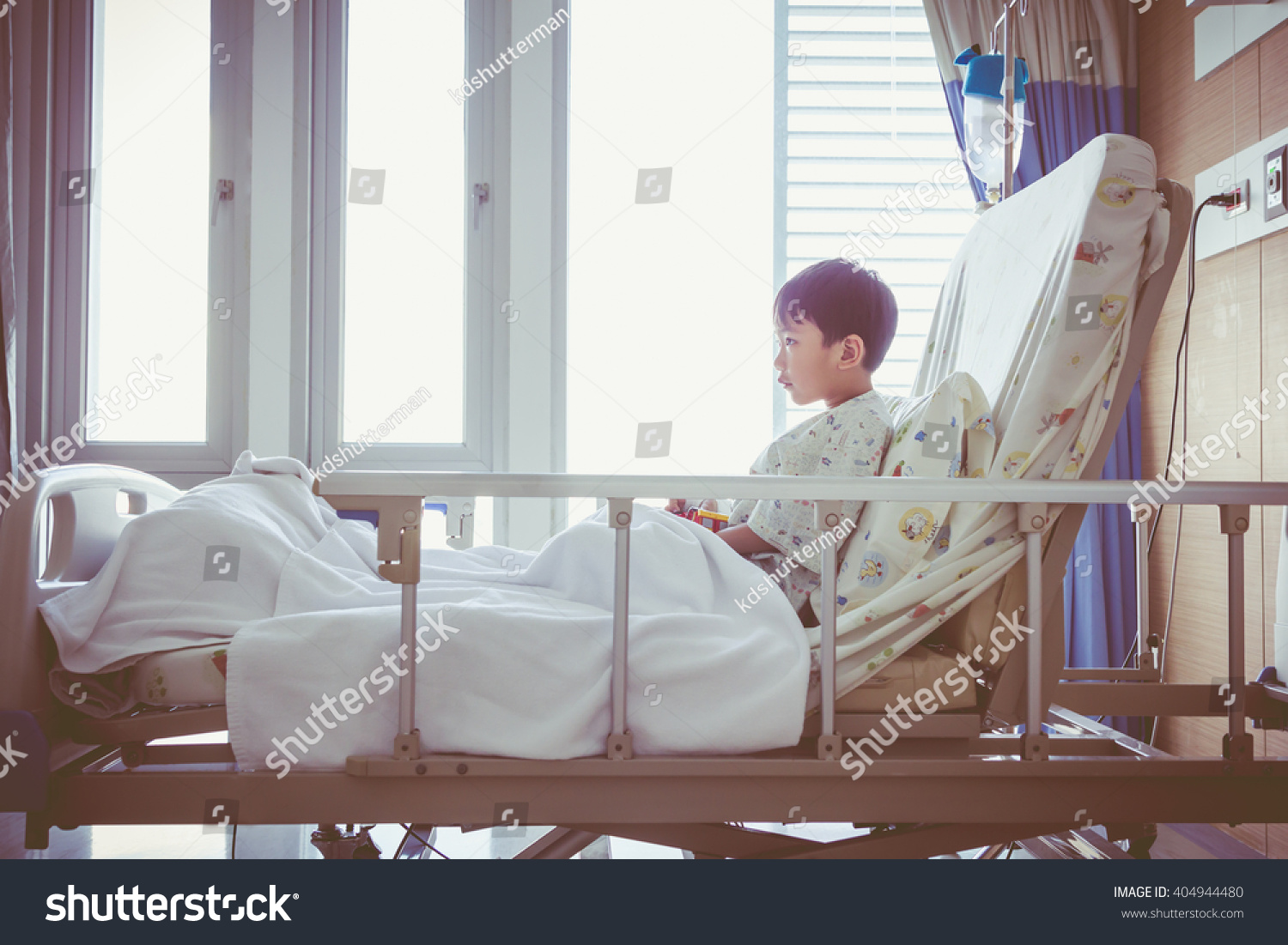 Illness asian child admitted at modern and comfortable equipped hospital room with infusion pump intravenous IV drip. Health care and people concept. Vintage style.
