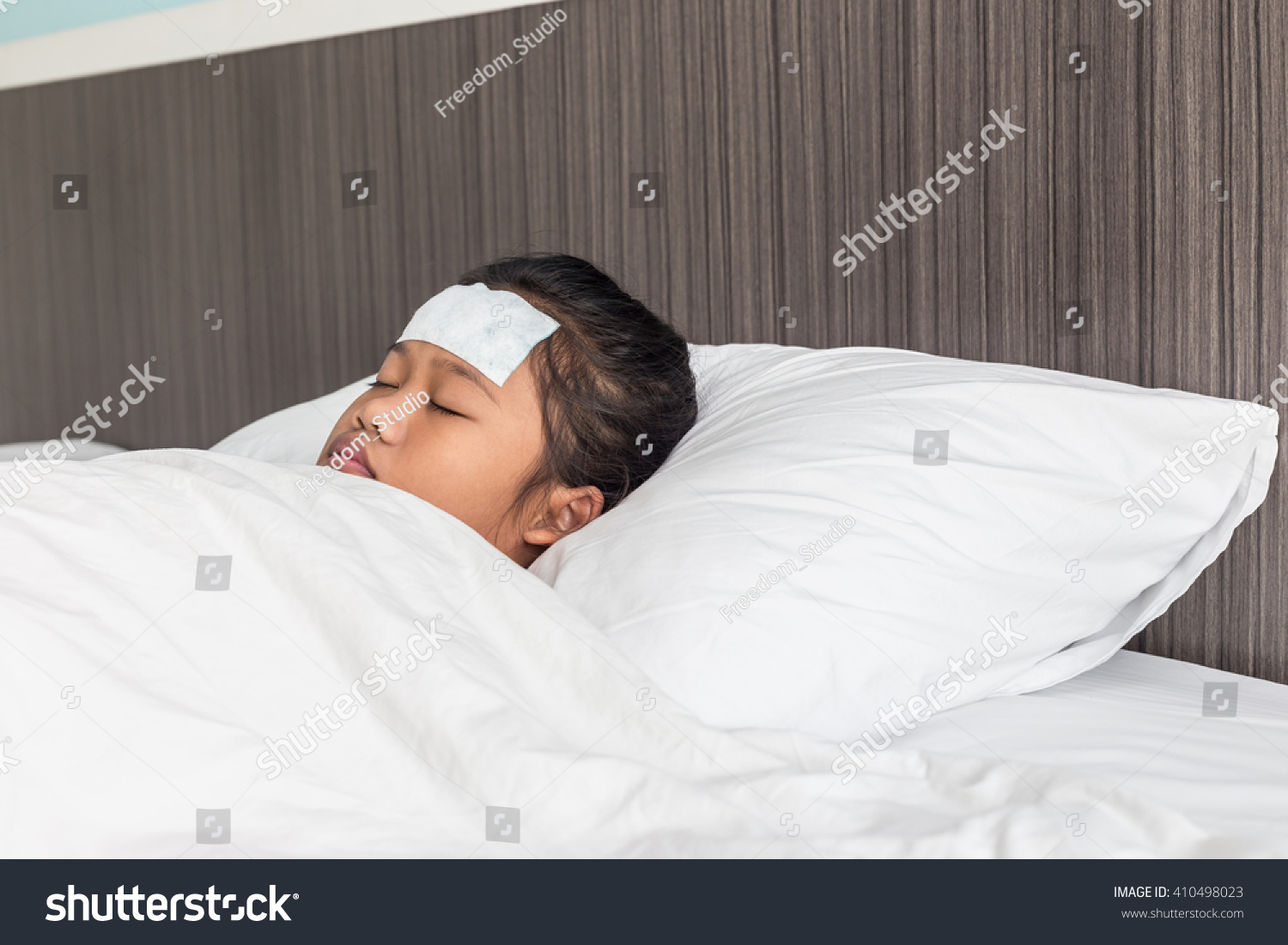 Children with white cool fever on forehead and sleeping on the bed
