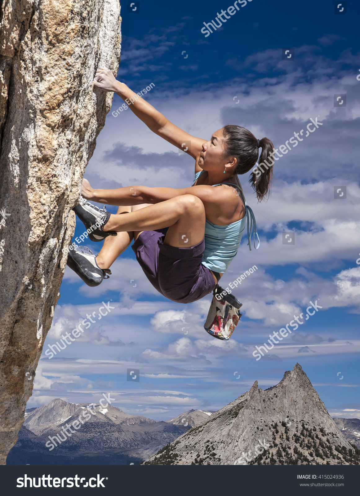 female climber dangles from the edge of a challenging cliff