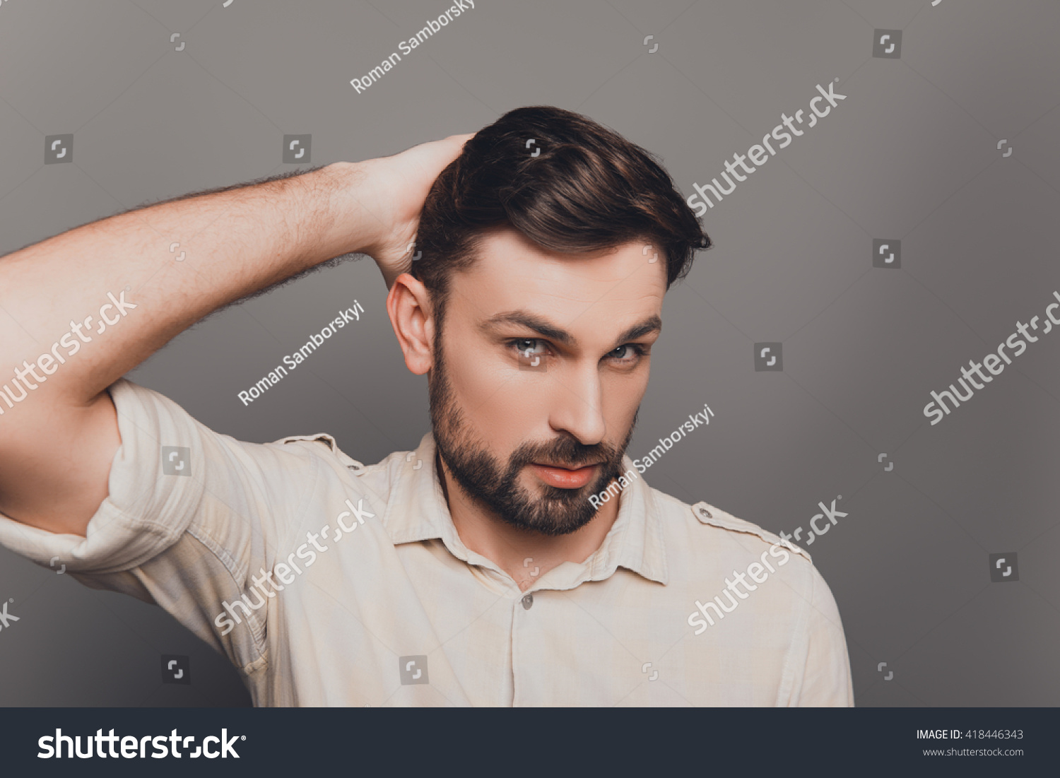 Portrait of handsome serious young man combing his hair