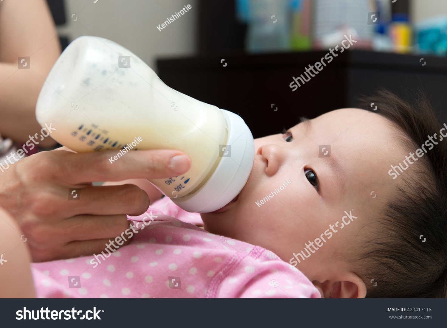 Mother feeding baby with milk from a bottle
