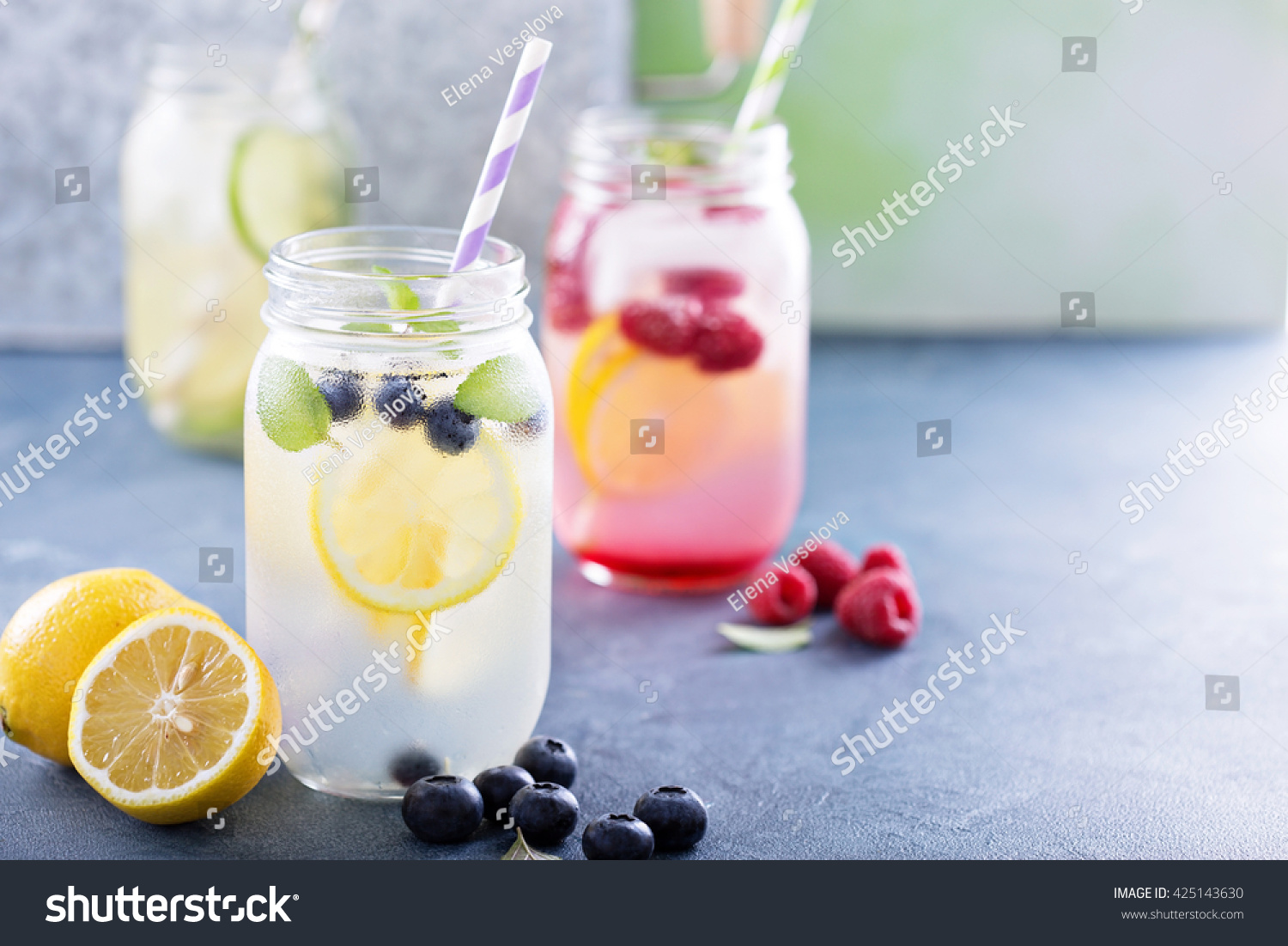Variety of lemonade in mason jars with berries and fruits