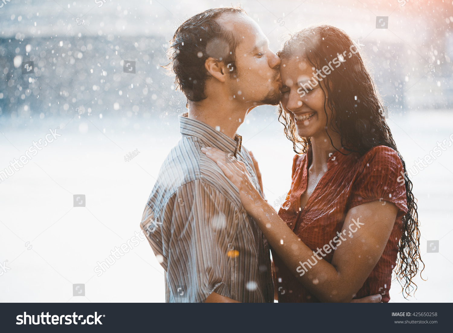 couple in love hugging and kissing under summer rain