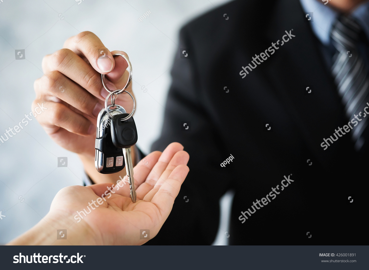 Car salesman giving the key to the new car owner transportation and ownership concept.
