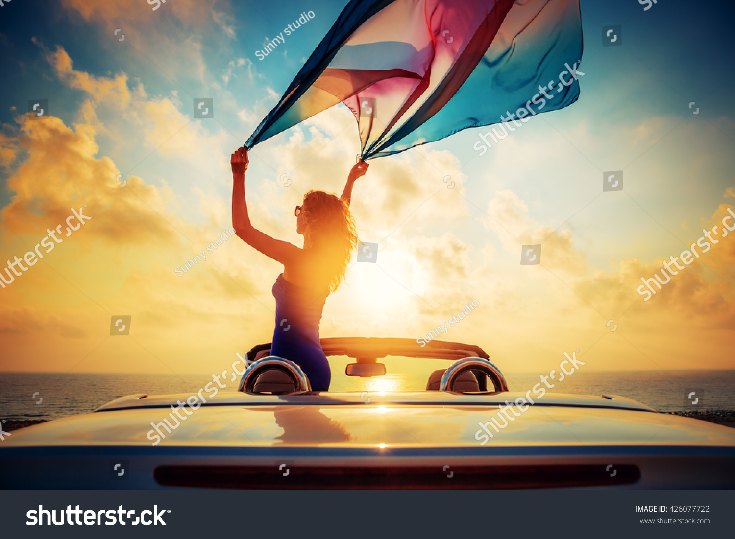 Silhouette of beautiful woman relaxing on the beach. Person having fun in cabriolet against blue sky background. Summer vacation and travel concept