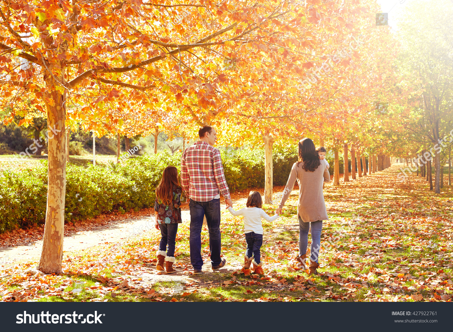 family walking in an autumn park with fallen fall leaves