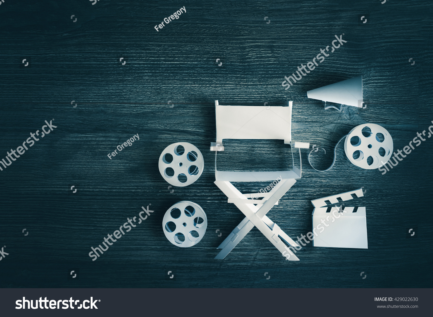 high contrast vintage image of Director chair and several movie items made from paper on a wood surface