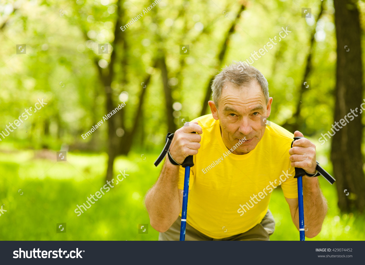 Tired senior man making nordic walking in the park