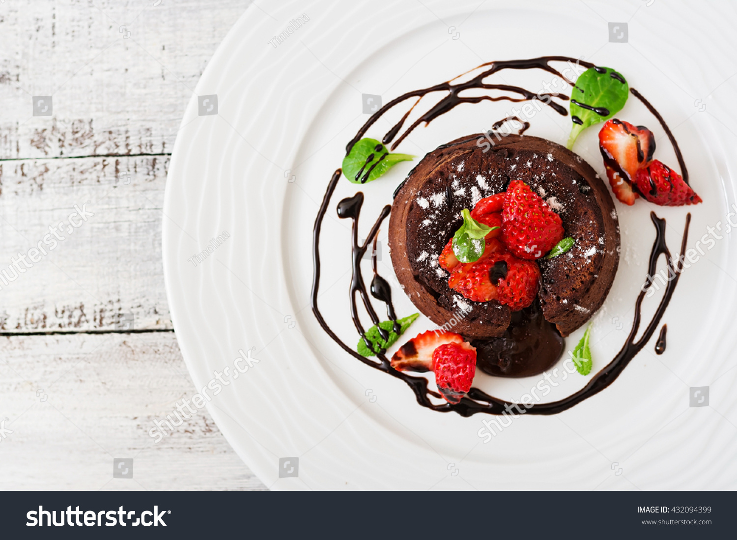 Chocolate fondant (cupcake) with strawberries and powdered sugar. Top view