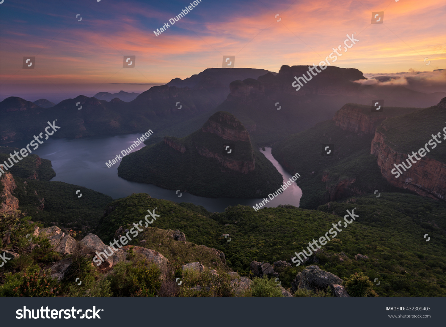 The sun paints high clouds in oranges over the Blyde River Canyon at sunrise
