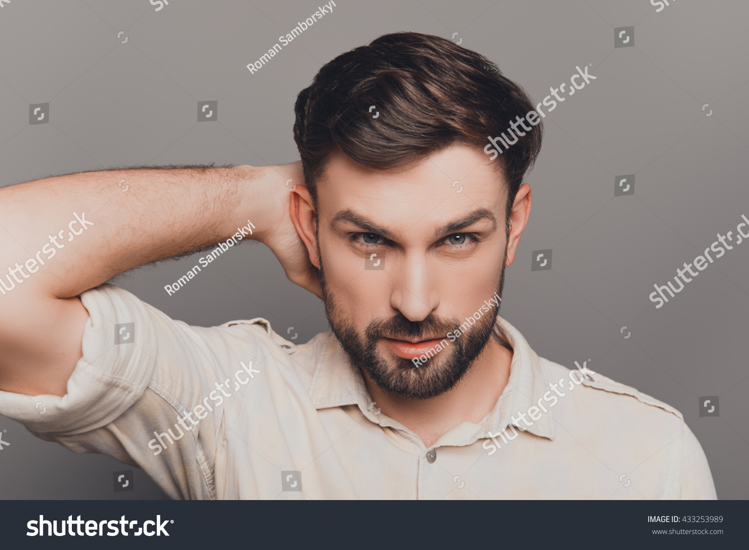 Handsome serious young man combing his hair with fingers