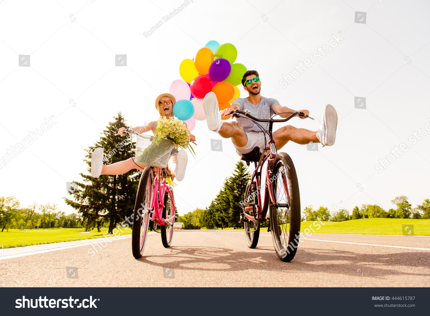 Happy funny young couple riding on bicycle with raised legs