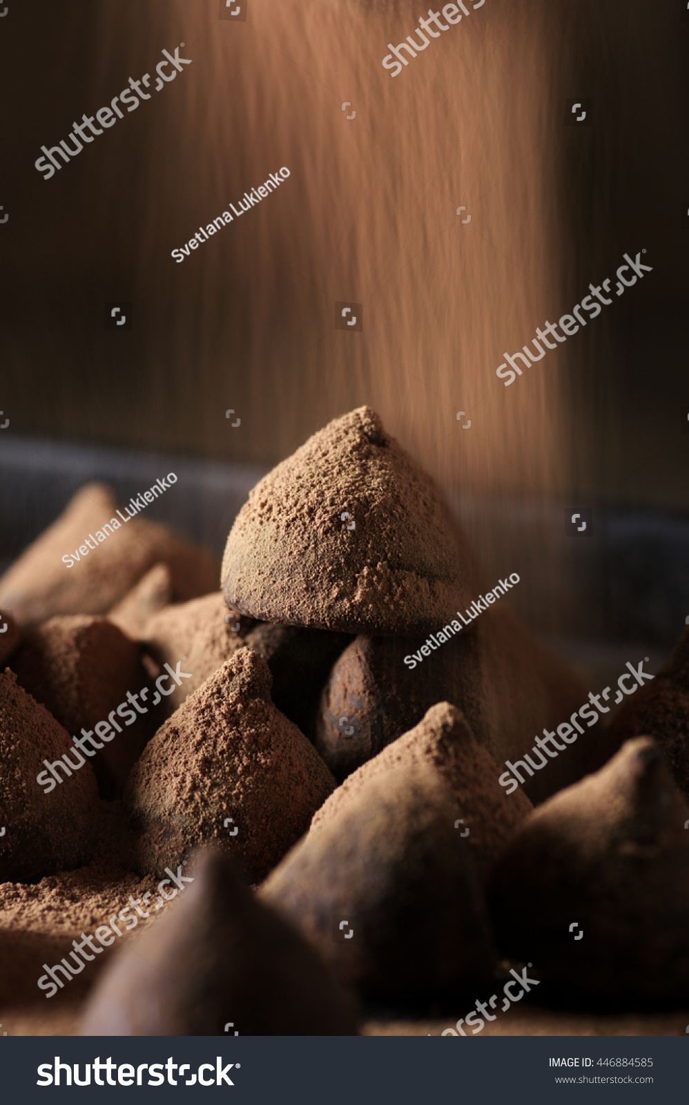 Homemade dark chocolate truffles with blurring pouring cocoa powder. Low light low shutter speed.