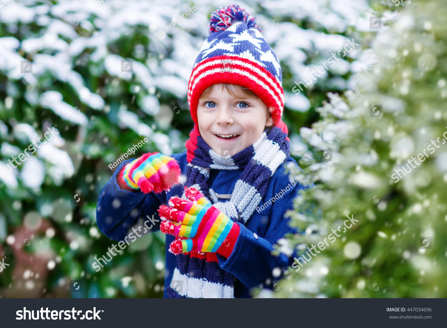Winter portrait of little kid boy in colorful clothes outdoors during snowfall. Active outdoors leisure with children in winter on cold snowy days. Happy child having fun with snow