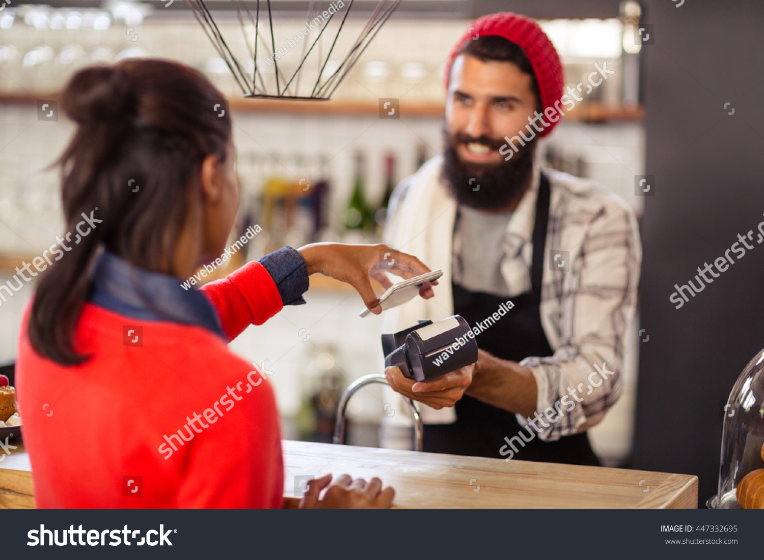 Seller taking payment with bank card reader and smartphone in the shop