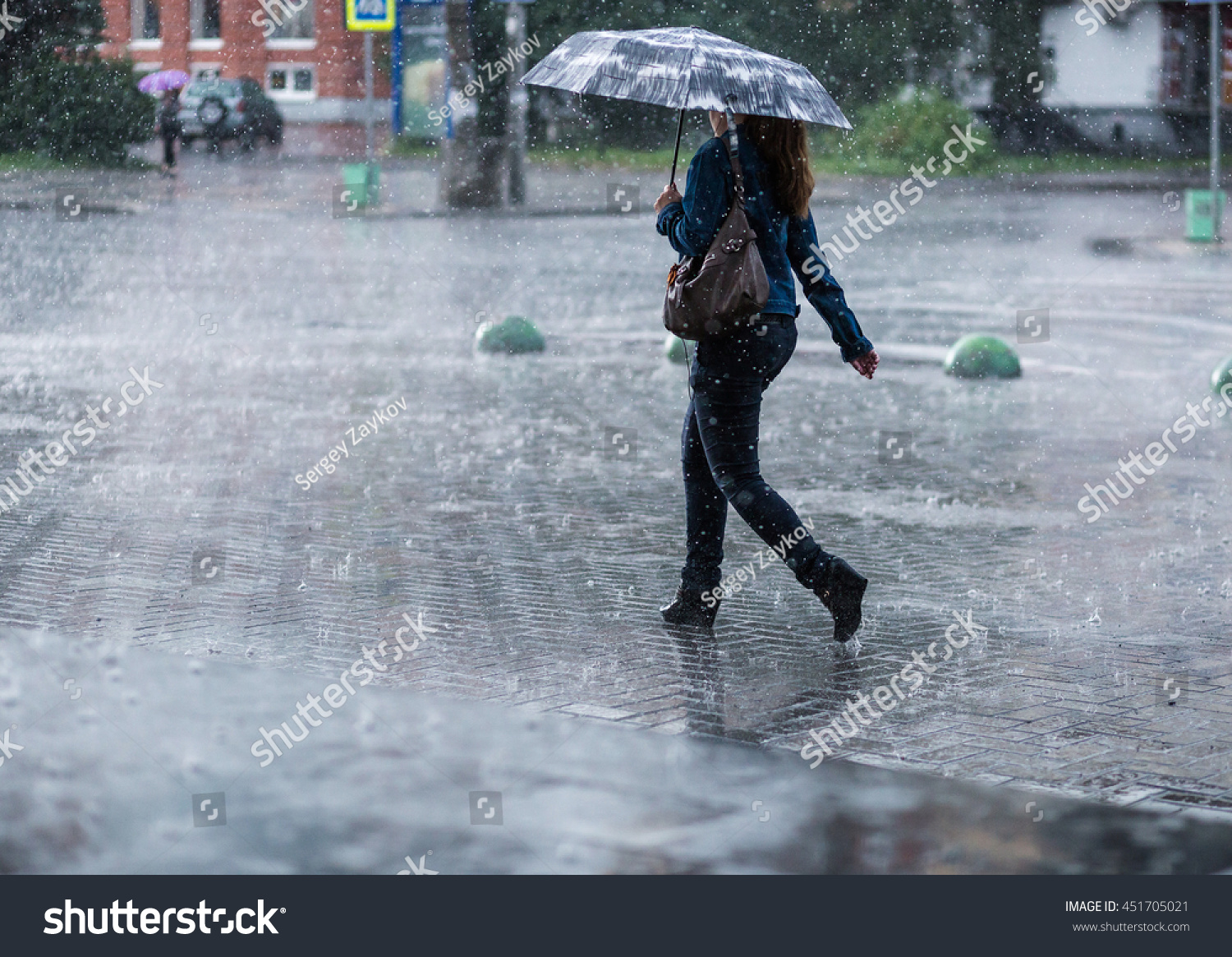 Woman with umbrella going on street during heavy rain .