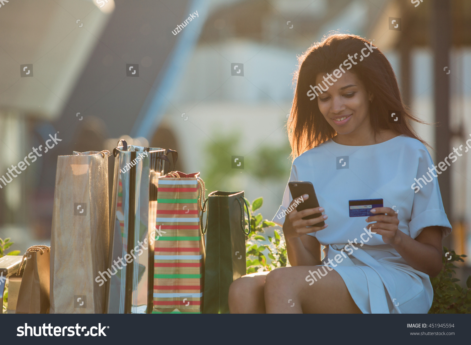 Woman holding a credit card and using cell phone for online shopping.