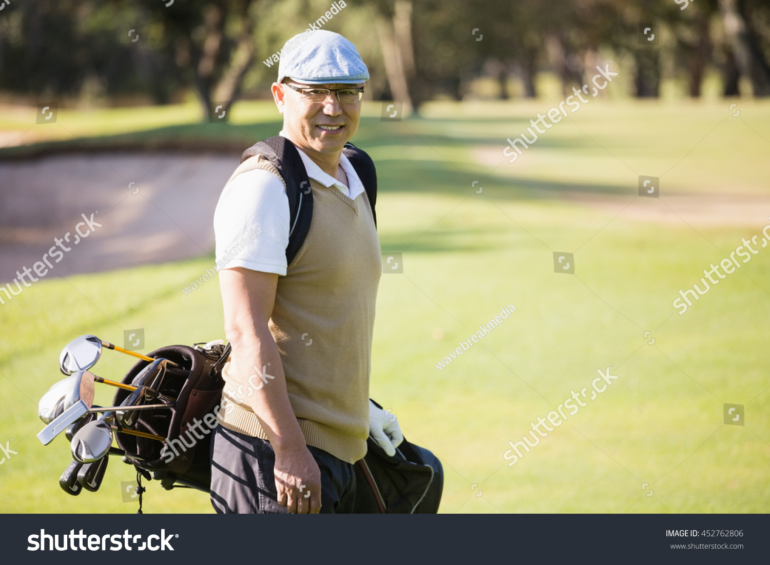 Sportsman posing with his golf bag on a field