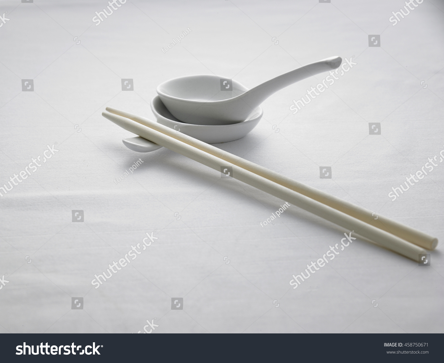 spoon and chopsticks on top of white table cloth