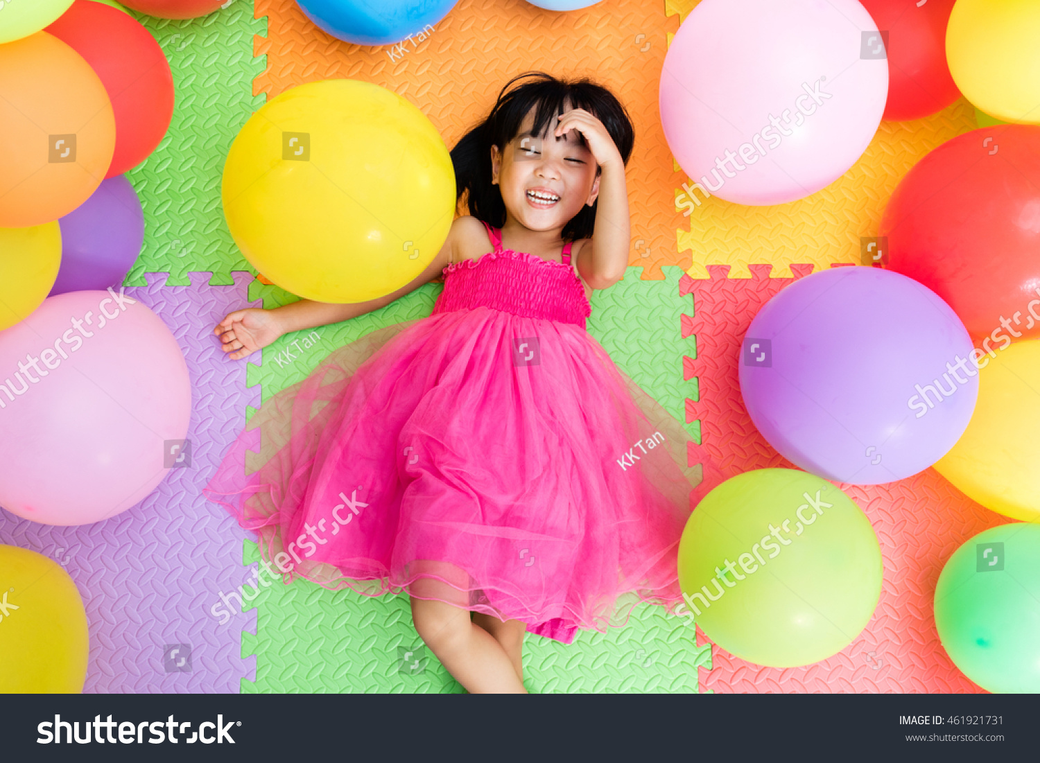 Asian Little Chinese Girl Lying on the Floor amongst Colorful Balloons in Indoor Playground
