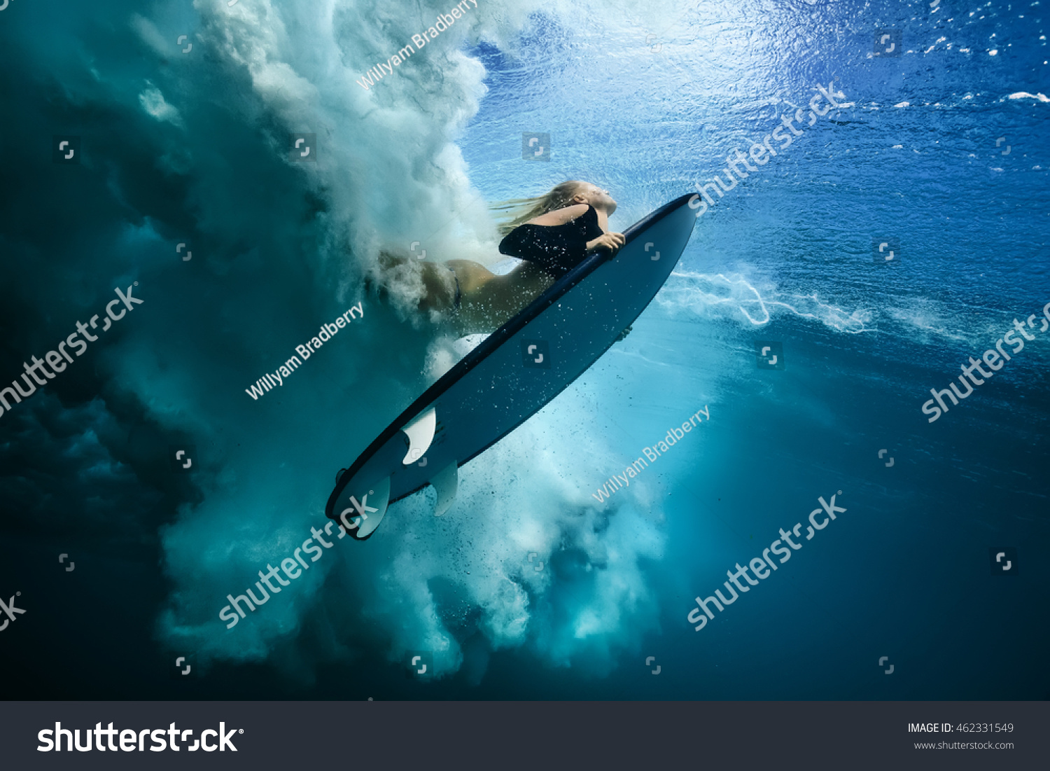 Beautiful Surfer Diving Duckdive under Big Ocean Wave. Turbulent air bubbles and tracks after sea wave crashing. Ripples at water surface with sky color.